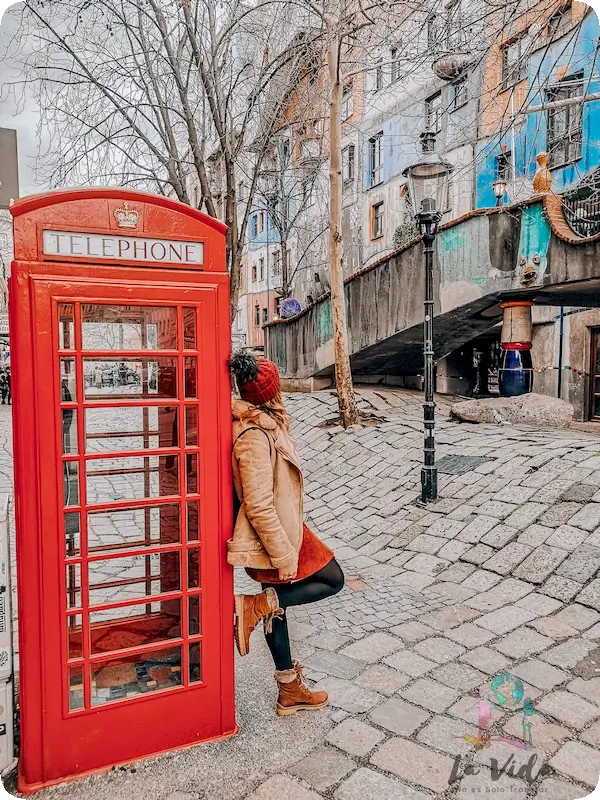 Judit apoyada en una cabina de telefono roja en Hundertwasserhaus Viena 